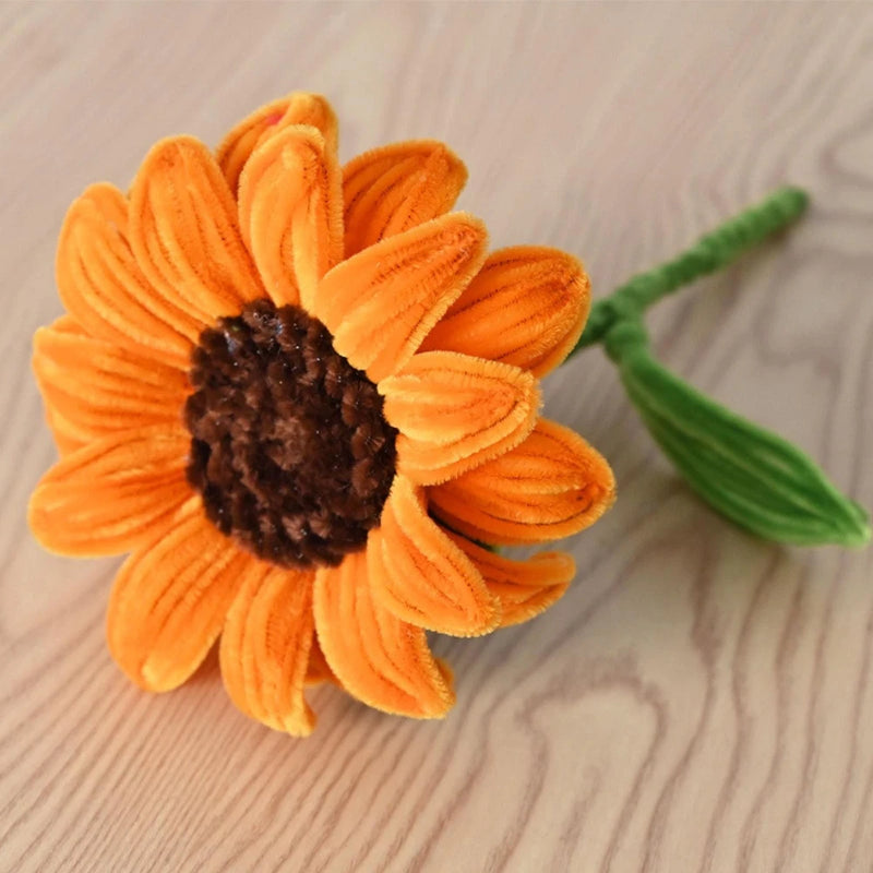 Orange artificial sunflower with dark center on green chenille stem