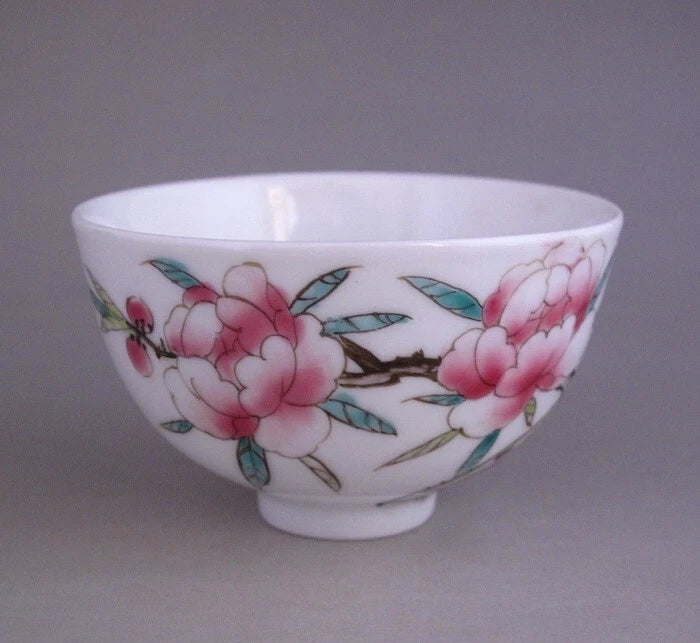 White porcelain teacup with pink peony flowers and green leafy accents