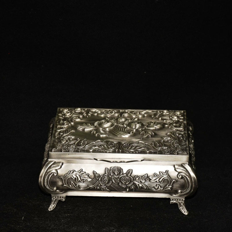 Ornate metallic jewelry box with hinged lid and engraved floral pattern, stand legs