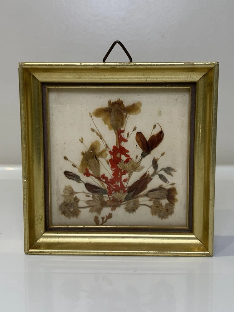 Framed mini dried flower artwork with gold border and pressed red and tan blooms