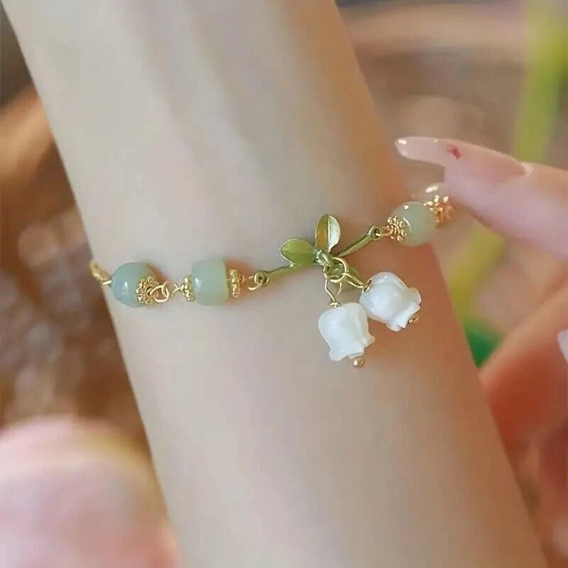 Green beaded bracelet with gold tone lily-of-the-valley flower charms
