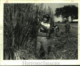 1987 Press Photo Chinh Nguyen cuts pampas grass near Lake Pontchartrain. Pampas Grass
