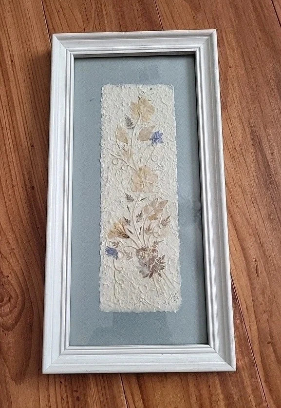 White framed pressed dried flowers art with beige floral panel and small blue accents