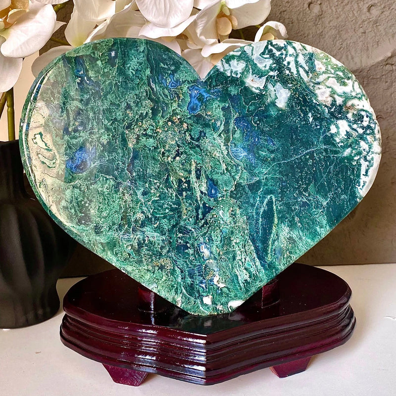 Green and blue heart-shaped crystal specimen on dark wooden base