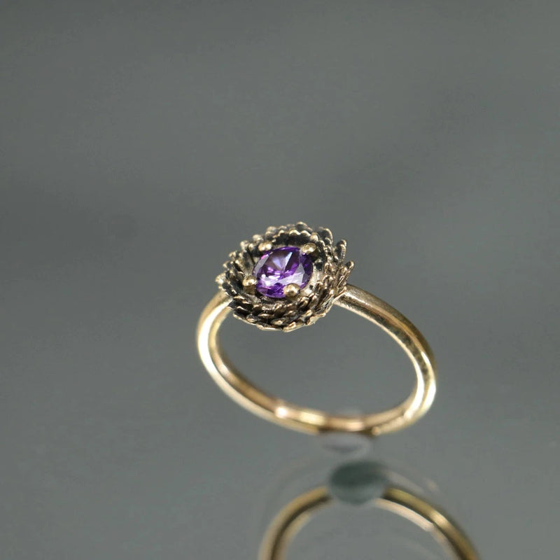 Gold-tone amethyst oval gemstone ring with ornate braided halo setting