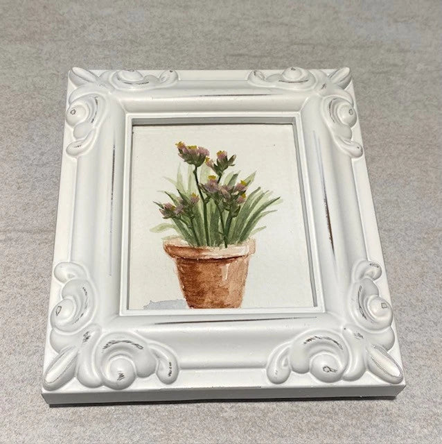 Pressed flower watercolor artwork in ornate white frame, small potted bouquet design