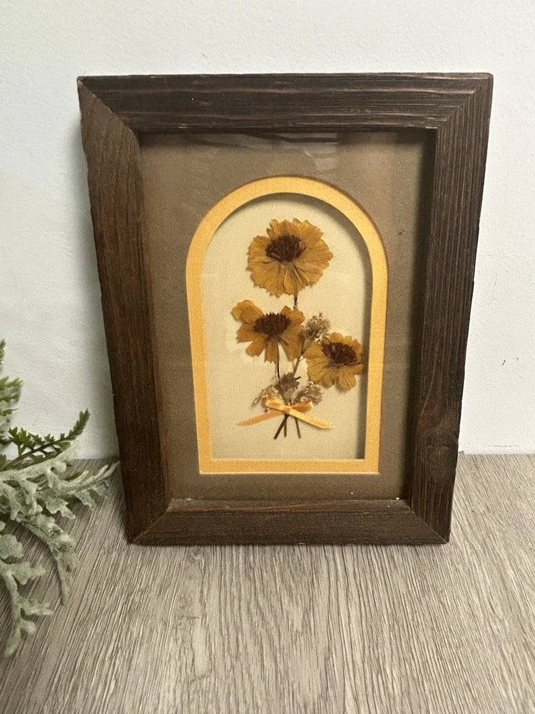 Framed pressed dried flower artwork with yellow blooms in dark wood frame