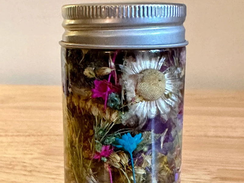 Glass herbarium jar with metal lid, filled with dried flowers and herbs