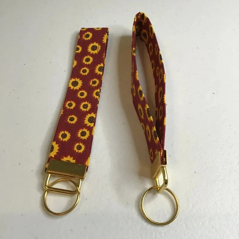 Sunflower patterned wristlet keychain with gold tone ring and clasp hardware
