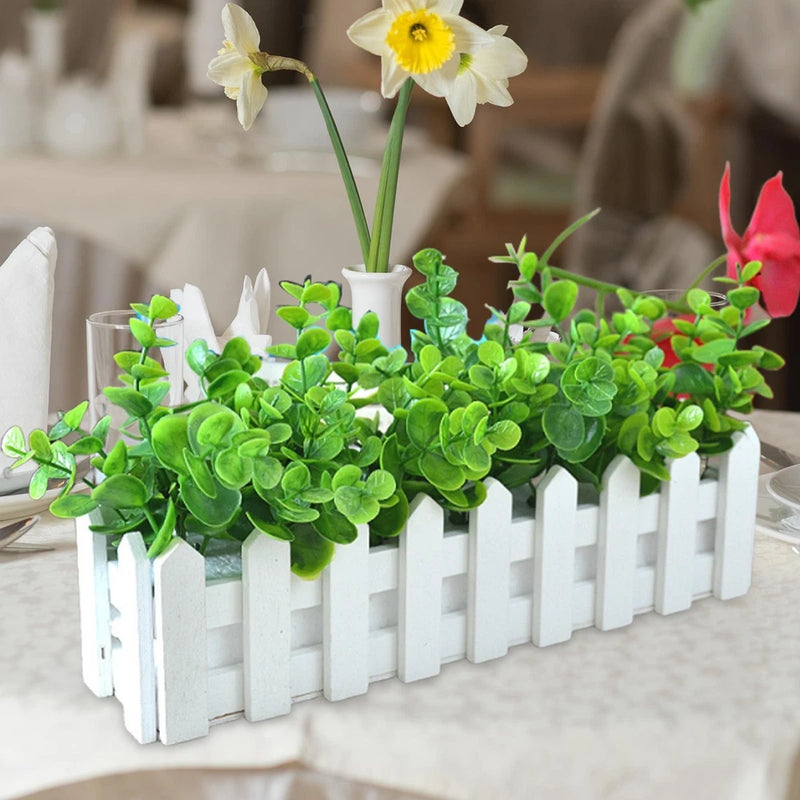 Artificial green potted plant desk ornament in white picket planter, with white flowers