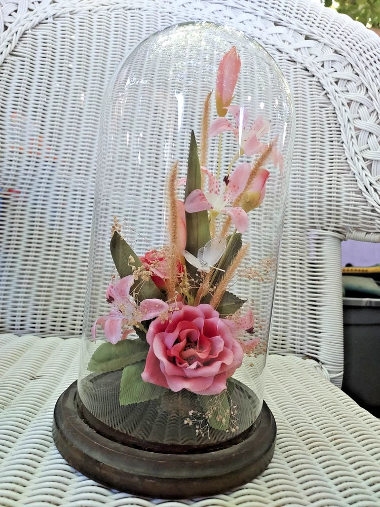Pink dried flower cloche under clear glass dome with rose and buds on dark base