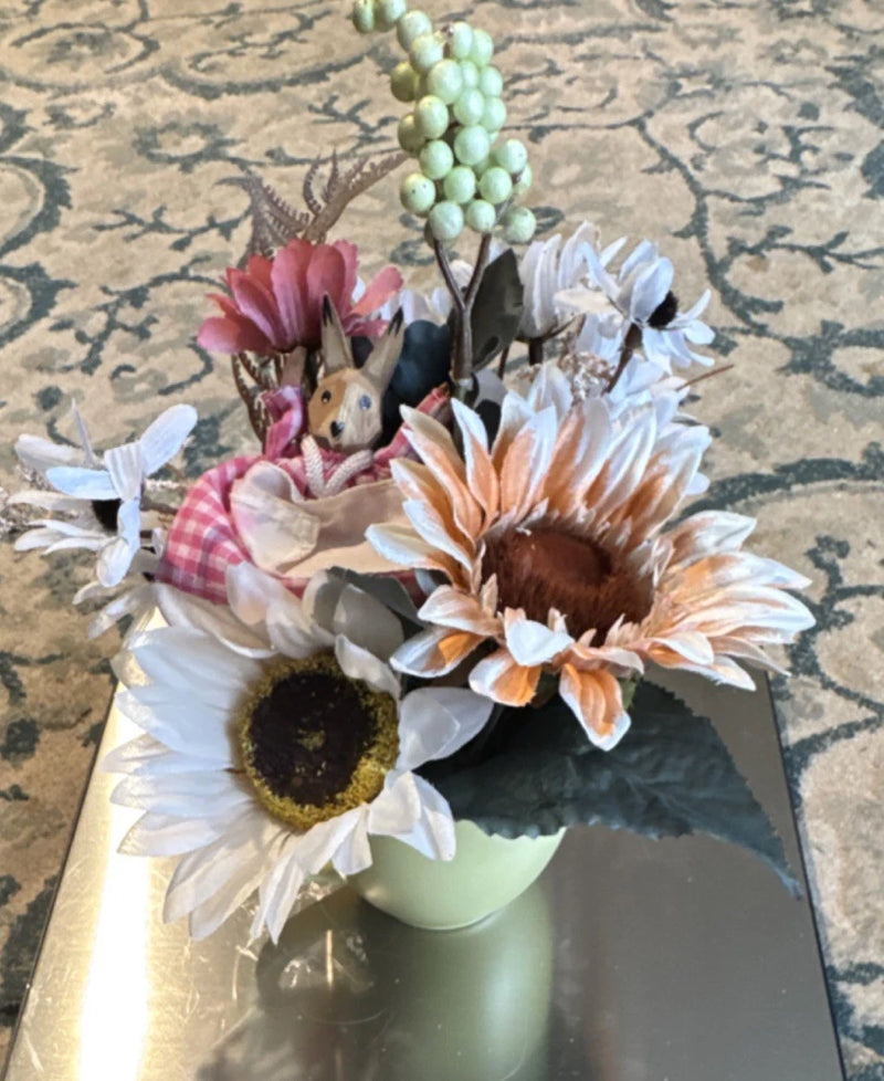Artificial sunflower and mixed flowers in green mug with small bunny figurine