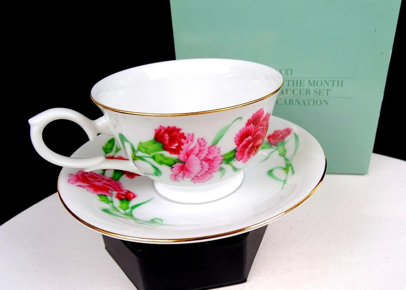 Vintage porcelain tea cup and saucer set with red carnations, white base, and gold trim