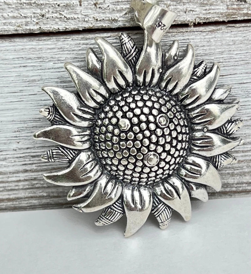 Sterling silver sunflower pendant with textured bead center and detailed petals