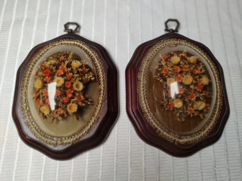 Pair of vintage wall art frames with dried floral bouquet under clear domes