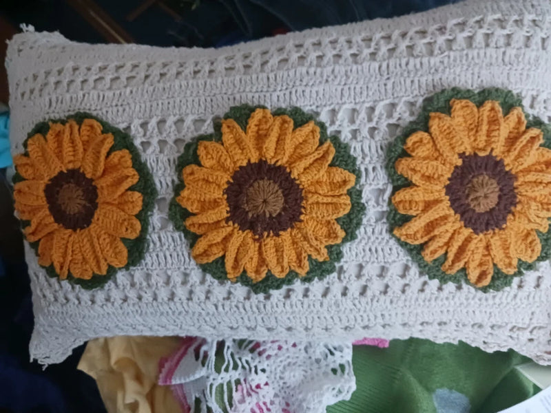 Cream crocheted rectangle pillow with three sunflower appliques in yellow and brown
