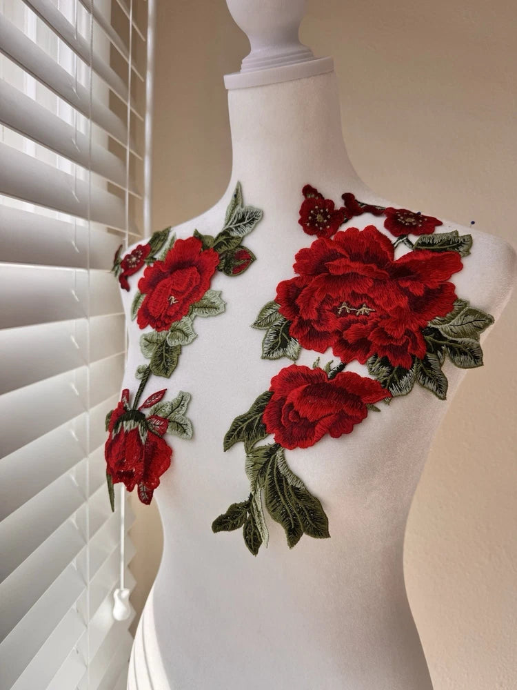 Set of red rose and green leaf embroidered applique patches on white fabric