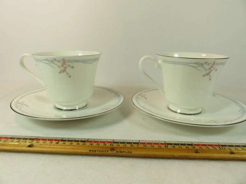 Pair of white footed tea cups with floral accents and matching saucers, 6 oz