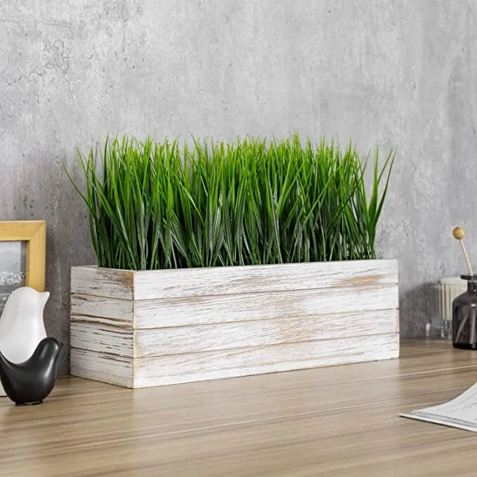Artificial green grass plant in a whitewashed wood rectangular window box planter