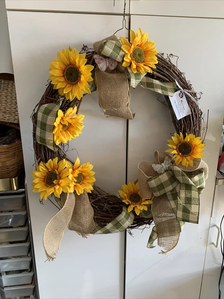 Round grapevine wreath with yellow sunflowers, burlap bow, and plaid ribbon loops
