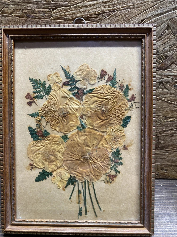 Wood-framed wall hanging with pressed beige flowers and green leaves bouquet