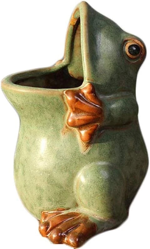 Ceramic frog planter pot with green glaze and brown raised details, holds small plants