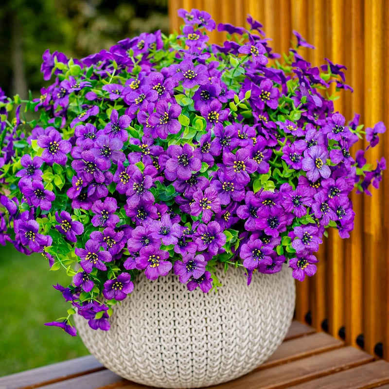 Artificial purple and green faux flower bundle in white woven planter pot