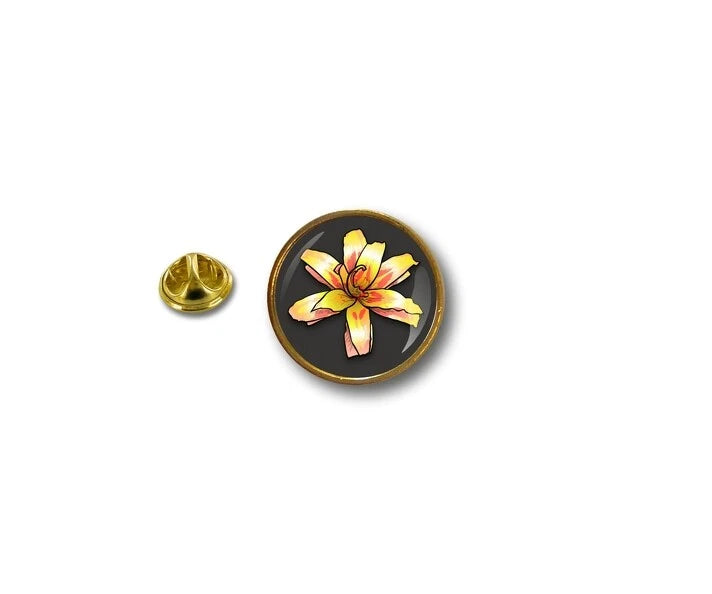 Round metal lapel pin with black enamel, gold border, and yellow flower design