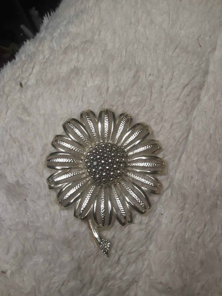 Large silver-tone sunflower brooch pin with textured petals and a rhinestone center