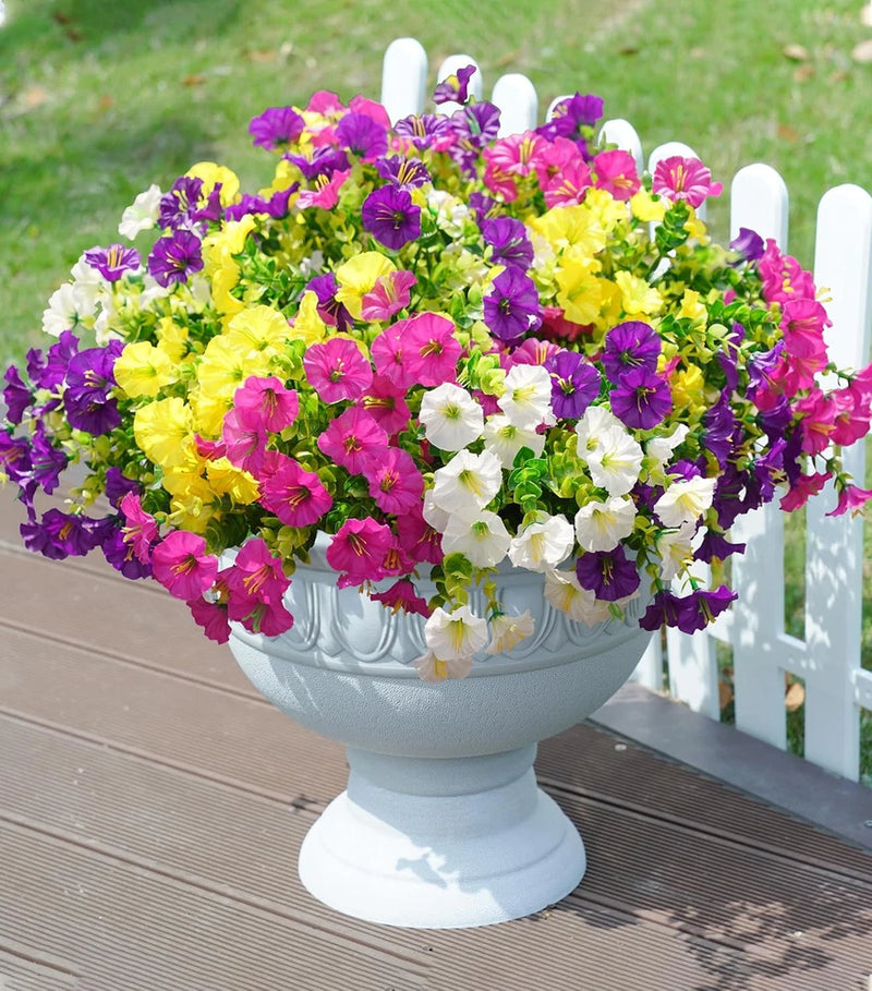 Artificial flower arrangement in a white pot with purple, pink, yellow and white faux blooms