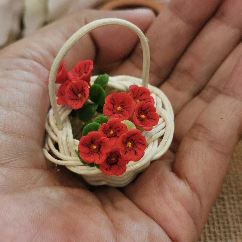 Miniature dollhouse bouquet in small wicker basket with red flowers and green leaves