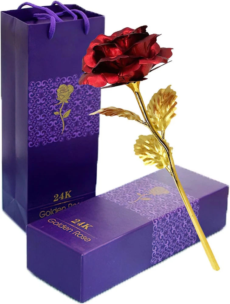 Artificial long-stem red rose with gold dipped leaves, beside purple gift box