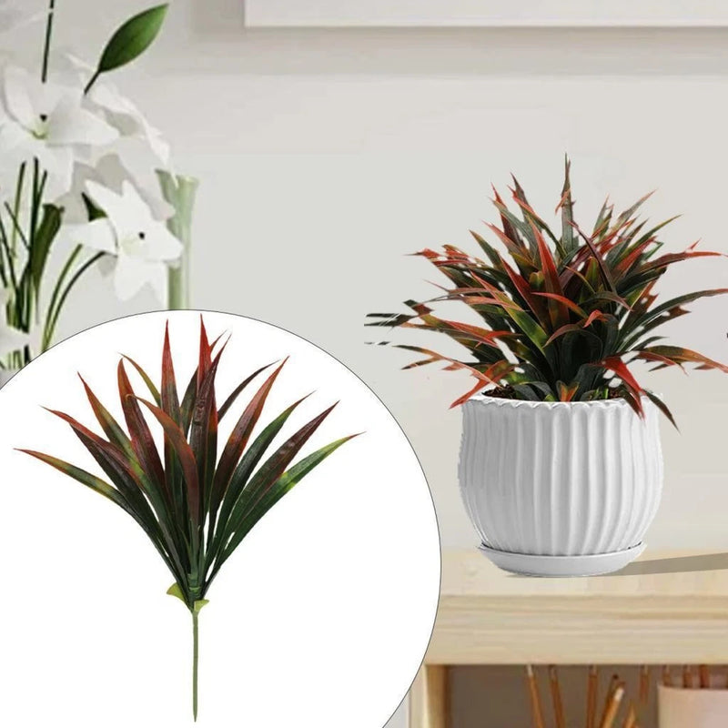 Faux greenery plant with spiky dark green leaves and reddish tips in white ribbed pot