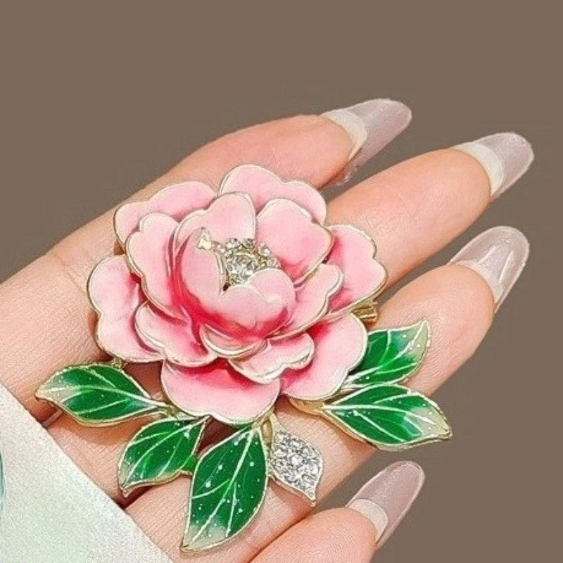 Peony flower brooch with pink enamel petals, green leaves, and gold-tone clasp