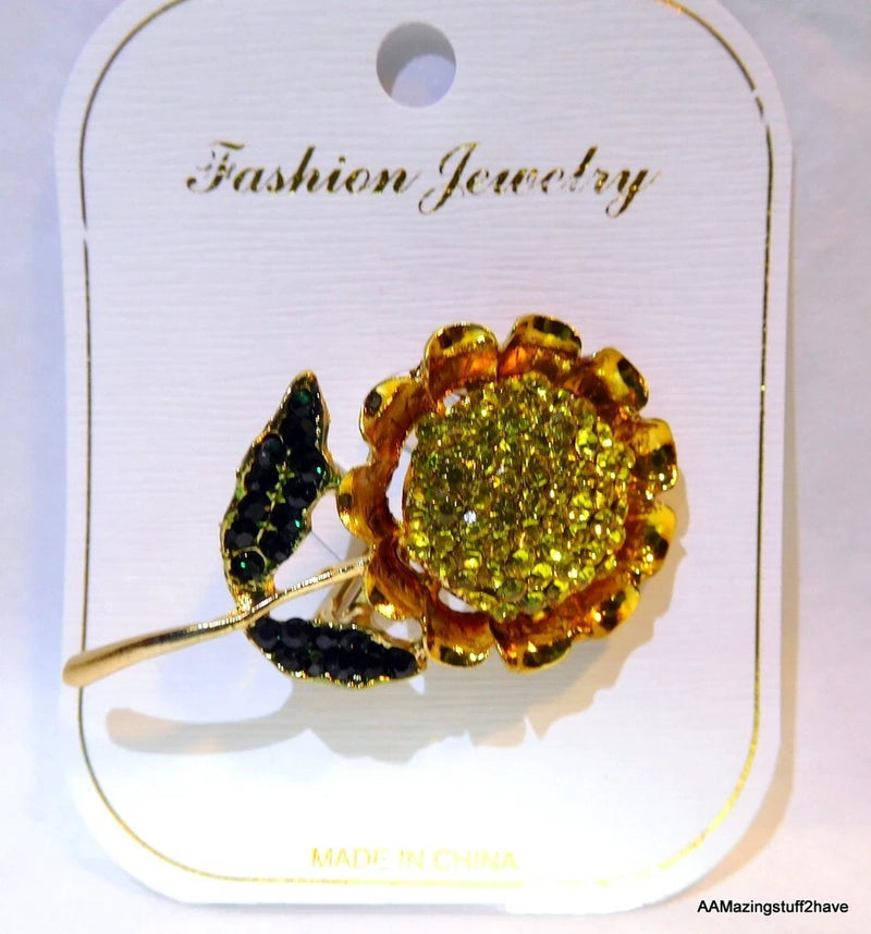 Gold-tone sunflower brooch pin with yellow-green glitter stones and dark leaf accents