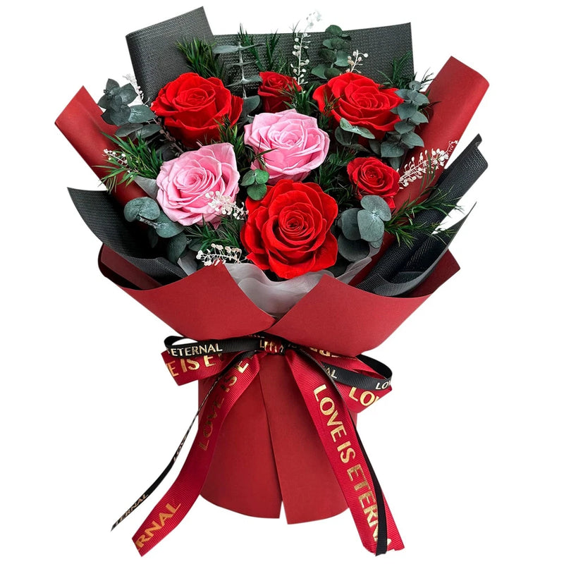 Preserved rose bouquet with red and pink roses, green leaves, red ribbon wrap