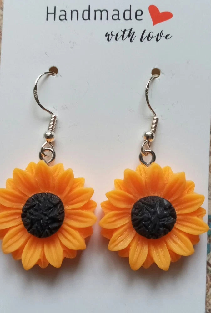 Sunflower dangle earrings with orange petals and dark textured centers, silver hooks