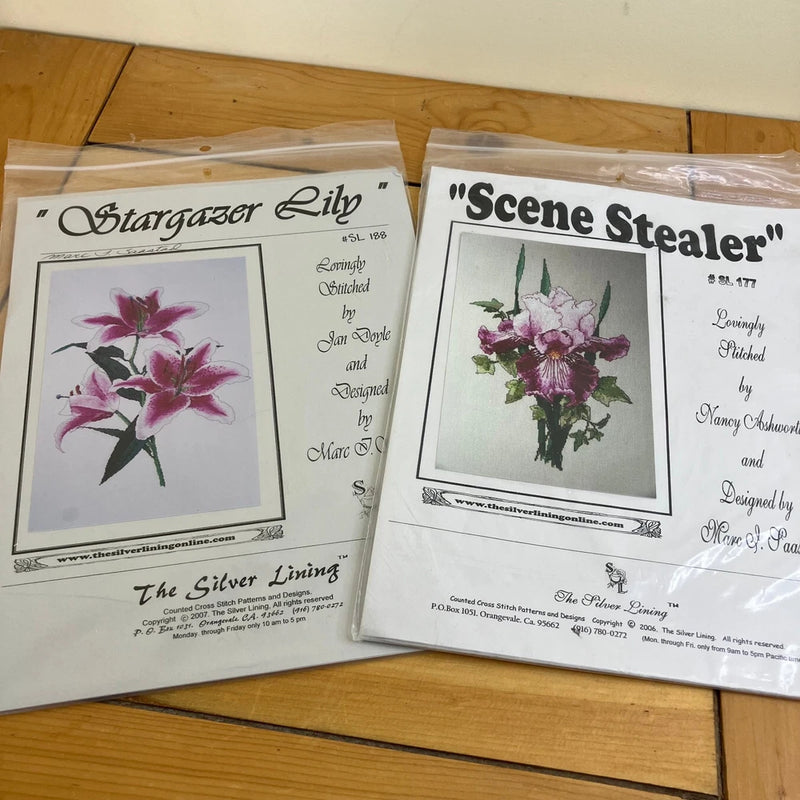 Purple flower cross stitch charts on paper slips in clear plastic, two designs shown