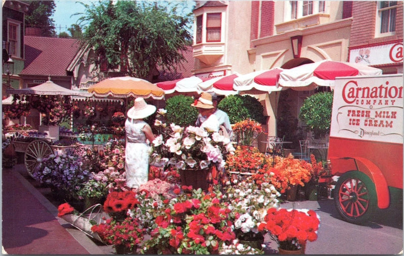 Vintage postcard showing a Carnation flower truck and colorful garden flowers