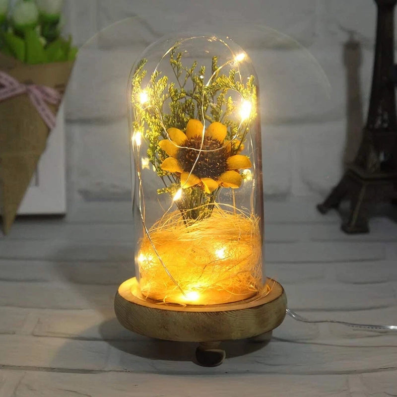 Artificial sunflower in glass dome with warm LED fairy lights, wooden base