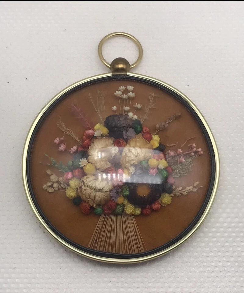 Round gold-tone framed dome wall art with dried flowers bouquet inside