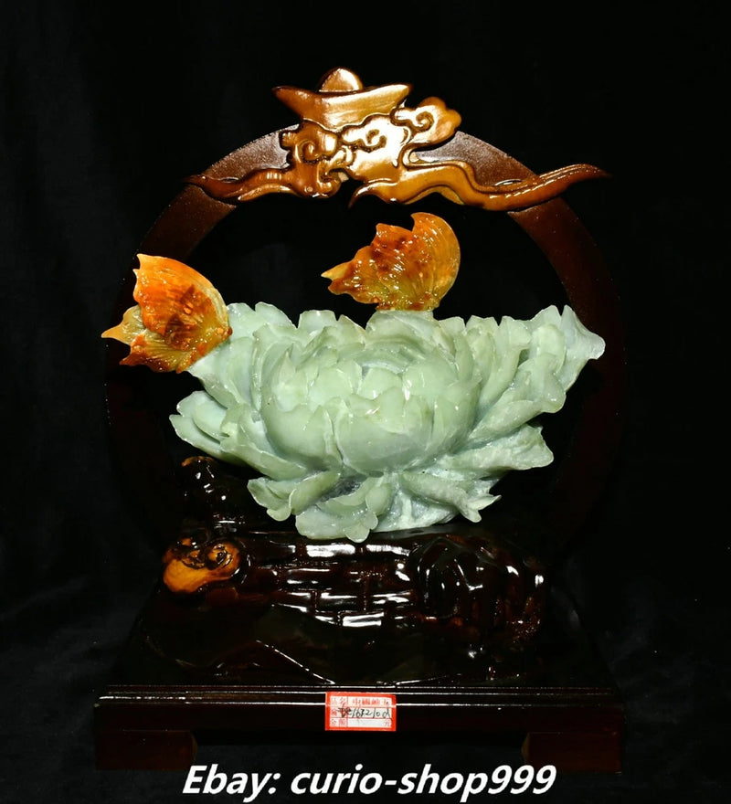 Carved jade peony flower with butterfly motif on dark wooden stand, decorative sculpture