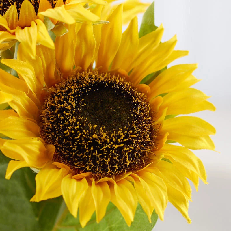 Artificial sunflower bloom with yellow petals and dark brown seed center