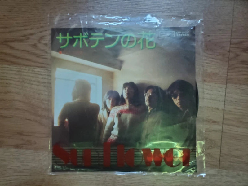 Plastic-wrapped album cover with group photo and green Japanese title text