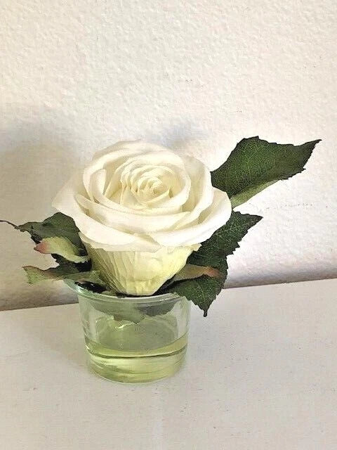 Artificial white rose arrangement in clear glass vase with faux water