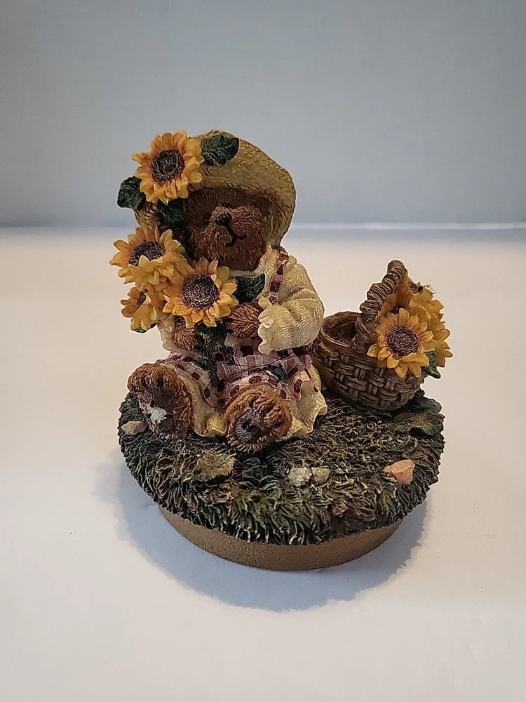 Sunflower candle topper featuring a bear figurine holding flowers with a basket on a round base