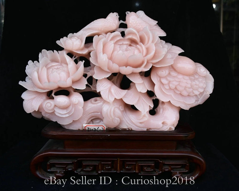 Pink carved jade ruyi sculpture with peony flowers and bird, on dark wooden stand