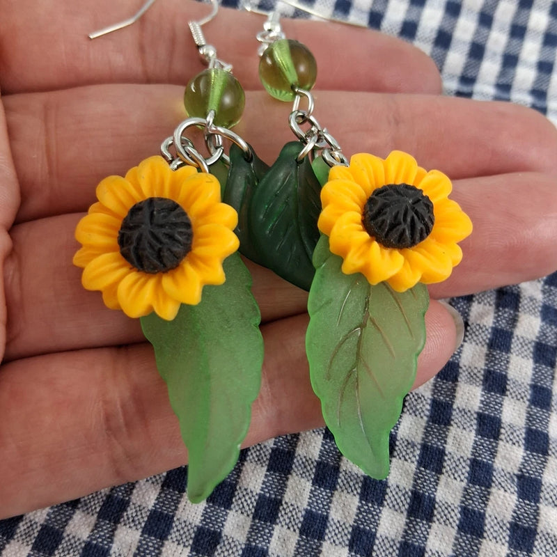 Sunflower and leaf dangle earrings with yellow blooms, dark centers, green leaves, silver hooks
