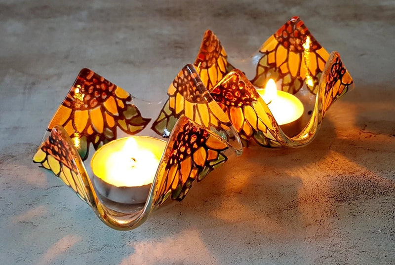 Pair of sunflower mosaic fused-glass candlesticks with lit candles