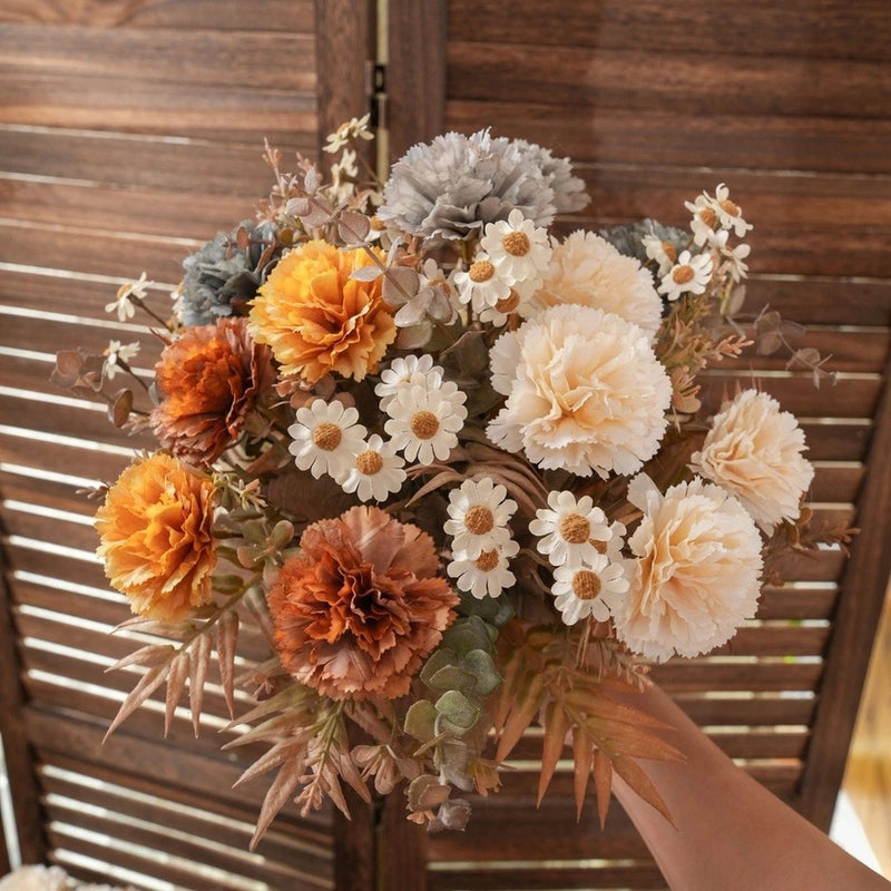 Silk flower bouquet with orange, cream, and white carnations and greenery, tied ribbon